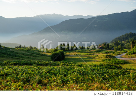 Beautiful landscape with mountains and a valley with house and road at sunset with blue sky. Beautiful landscape with mountains and a valley with house and road at sunset with blue sky. 118914418