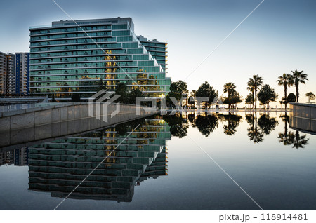 View of a modern beautiful building with glass balconies with a lake in the foreground. View of a modern beautiful building with glass balconies with a lake in the foreground. 118914481
