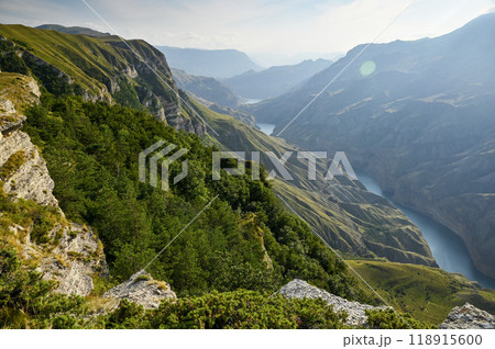 A beautiful landscape of mountains with bushes, rocks and a blue river on a summer day at sunset. A beautiful landscape of mountains with bushes, rocks and a blue river on a summer day at sunset. 118915600