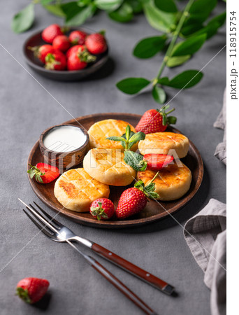 Cottage cheese, cheesecakes or syrniki with sour cream, strawberries and mint leaves Cottage cheese, cheesecakes or syrniki with sour cream, strawberries and mint leaves 118915754