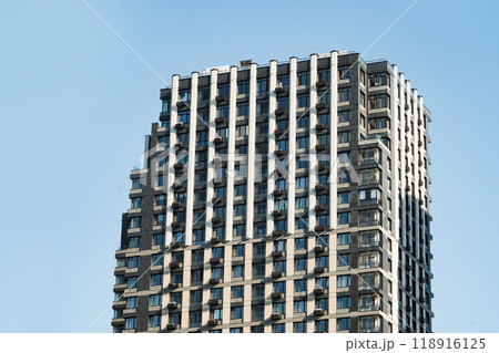 New building apartment with modern design. Minimal architecture skyscraper against blue cloudy sky. 118916125