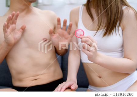 避妊具着用を勧める女性と断る男性　コンドームを持つ若い女性の手　夫婦　妊活　性的同意 118916260