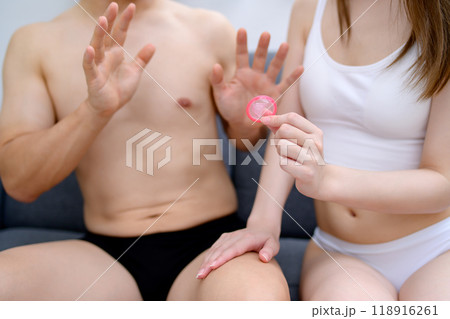 避妊具着用を勧める女性と断る男性 コンドームを持つ若い女性の手 夫婦 妊活 性的同意 避妊具着用を勧める女性と断る男性 コンドームを持つ若い女性の手 夫婦 妊活 性的同意 118916261
