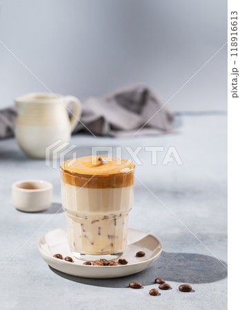 Dalgona coffee. Whipped instant coffee in a glass with coffee beans on a blue background  118916613