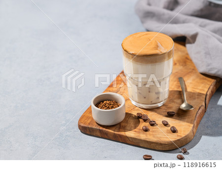 Dalgona coffee. Whipped instant coffee in a glass on a wooden board with coffee beans Dalgona coffee. Whipped instant coffee in a glass on a wooden board with coffee beans 118916615