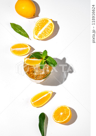 Flat lay of Iced tea with lemon and mint on white background with a shadow and citrus fruits. Flat lay of Iced tea with lemon and mint on white background with a shadow and citrus fruits. 118916624