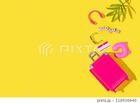 Flat lay pink toy suitcase with travel accessories on a yellow background. Travel concept. 118916640
