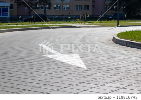 A white directional arrow, indicating right, is painted on the sidewalk A white directional arrow, indicating right, is painted on the sidewalk 118916745