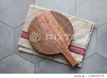 Empty wooden cutting board with napkin on gray ceramic tile in hexagon shape. Empty wooden cutting board with napkin on gray ceramic tile in hexagon shape. 118916779