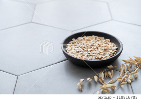Oatmeal in a wooden plate on a gray concrete tile with dry branch. 118916785