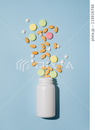 A variety of tablets and nutritional supplements of different colors are dynamically poured out  118916788