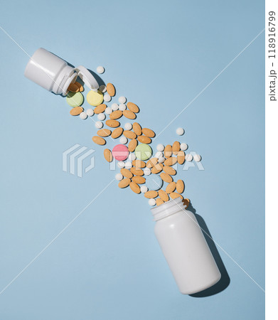 A variety of tablets and nutritional supplements of different colors are dynamically poured out  118916799