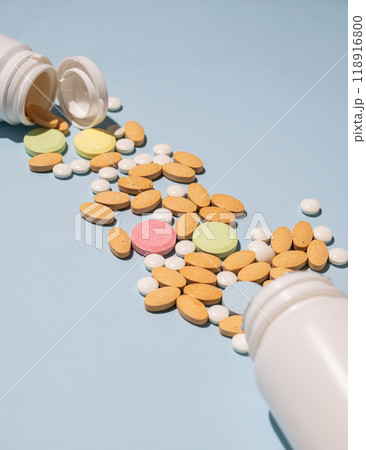 A variety of tablets and nutritional supplements of different colors are dynamically poured out  118916800