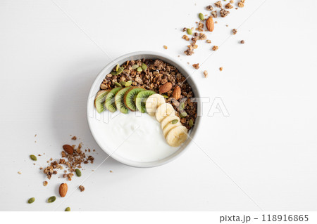 Granola and milk product with banana and kiwi on a white table. 118916865