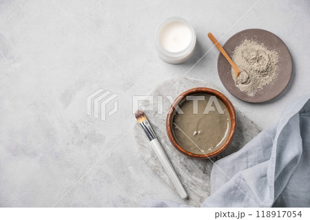 Organic cosmetic with blue clay on a marble board with brush, candle and napkin on light background. Organic cosmetic with blue clay on a marble board with brush, candle and napkin on light background. 118917054