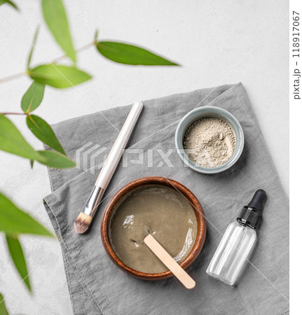 Flat lay of organic cosmetic with blue clay, serum,  brush and branch on a light background. 118917067