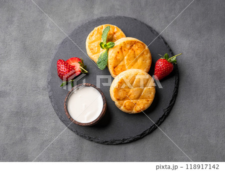Cottage cheese, cheesecakes or syrniki with sour cream, strawberries and mint leaves  118917142