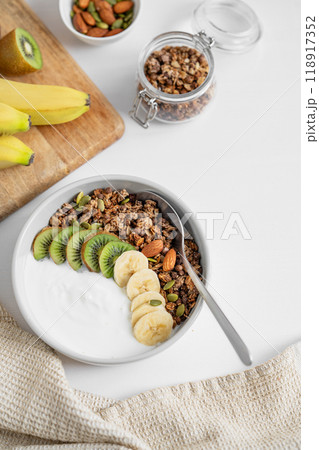 Granola and milk product with banana and kiwi on a white table. Granola and milk product with banana and kiwi on a white table. 118917352