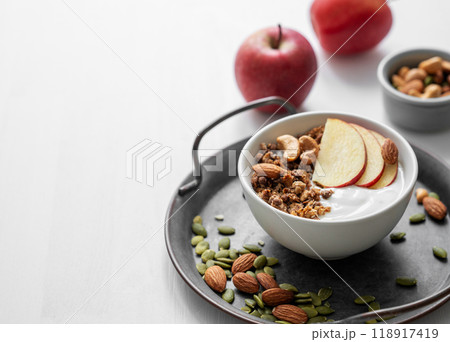 Healthy breakfast. Homemade granola or muesli with apple and nuts in a bowl on a white background. 118917419