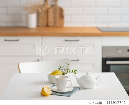 A cup of tea with lemon and a teapot on a white table. A cup of tea with lemon and a teapot on a white table. 118917742