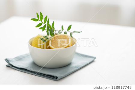 Fresh lemons in a bowl on a white wooden table in front of a window with morning natural light. Fresh lemons in a bowl on a white wooden table in front of a window with morning natural light. 118917743