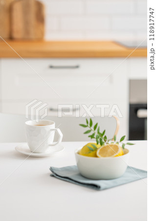 A cup of tea with lemon and a teapot on a white table. A cup of tea with lemon and a teapot on a white table. 118917747