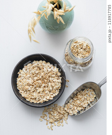 Oatmeal in a plate, jar and in a scoop on a white textured background. 118917785