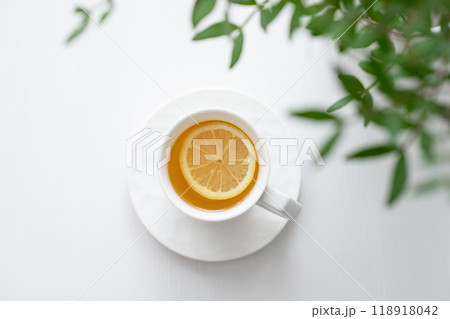 A cup of tea with lemon and green branch on a white table. A cup of tea with lemon and green branch on a white table. 118918042