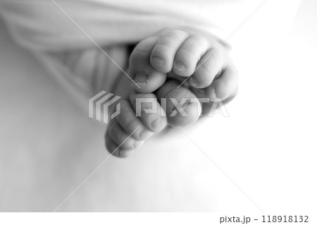 Foot of a newborn. Close up feet, toes, heels, feet of a newborn baby. Studio monochrome, vintage style, black and white macro photography. Foot of a newborn. Close up feet, toes, heels, feet of a newborn baby. Studio monochrome, vintage style, black and white macro photography. 118918132