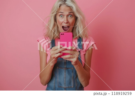 An older woman is holding a cell phone and laughing 118919259