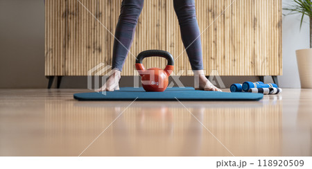An 8 kilogram kettlebell weight placed between female feet standing on an exercise mat An 8 kilogram kettlebell weight placed between female feet standing on an exercise mat 118920509