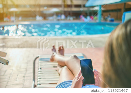 Young Beautiful using mobile phone sitting on chair in swimming pool. 118921467