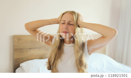 Exhausted woman with headache, pain tension in head, suffers from migraine lying in bed at home 118921501