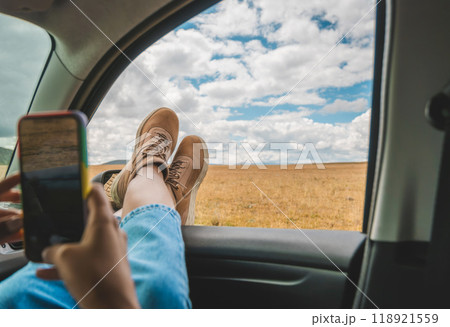 A woman is laying in a car with her legs up and a hat on. A woman traveling through the peruvian andes, Huayllay Stone Forest, Peru. 118921559