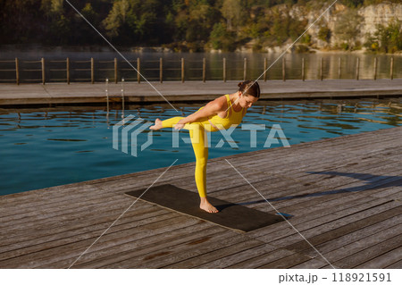 Experience a Serene Yoga Pose by the Water while dressed elegantly in Yellow Attire 118921591