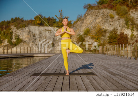 Experience a serene yoga pose on a beautiful scenic dock surrounded by vivid autumn colors 118921614