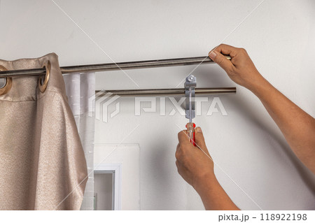 Worker repairman hanging and fixing the curtain on the window 118922198