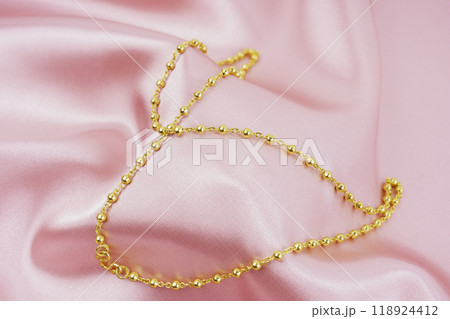 A Gold Necklace on pink color silk background. 118924412