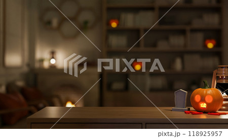 A wooden table featuring a Halloween pumpkin light and festive Halloween decor in a room at night. 118925957