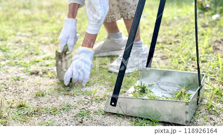 軍手をして雑草をシャベルで抜く高齢女性の手元と塵取り 軍手をして雑草をシャベルで抜く高齢女性の手元と塵取り 118926164