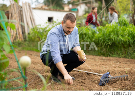Guy is planting seeds in open ground Guy is planting seeds in open ground 118927119