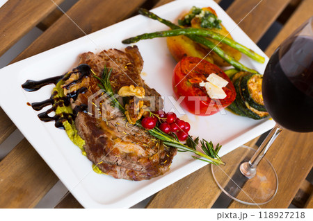 Grilled veal loin with guacamole and vegetables on wooden background Grilled veal loin with guacamole and vegetables on wooden background 118927218