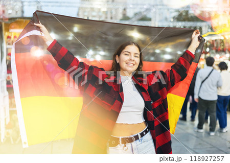 Smiling girl with German flag walking on street Christmas fair 118927257