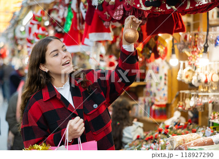 Smiling girl viewing golden bauble at street Christmas fair Smiling girl viewing golden bauble at street Christmas fair 118927290