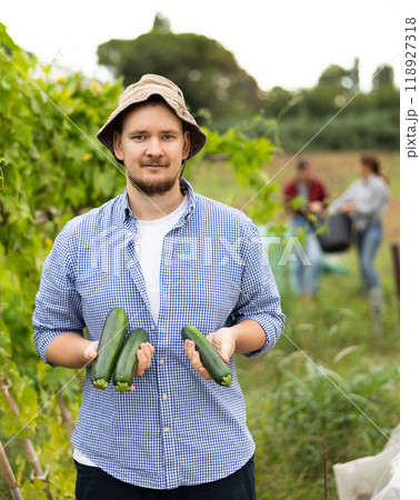 Portrait of happy man with harvest of cucumbers in her hands in field Portrait of happy man with harvest of cucumbers in her hands in field 118927318