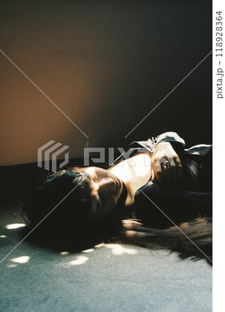 暗い部屋で床に寝そべる女性 暗い部屋で床に寝そべる女性 118928364