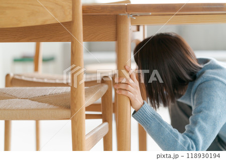 テーブルの下に避難する女性 118930194