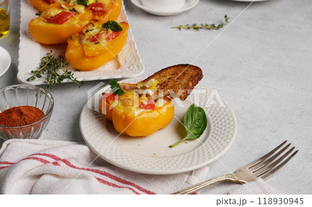 Variation of healthy breakfast with eggs baked in yellow pepper with cream cheese, ham and tomato on the plate with braed, on gray background. Food concept. copy space Variation of healthy breakfast with eggs baked in yellow pepper with cream cheese, ham and tomato on the plate with braed, on gray background. Food concept. copy space 118930945