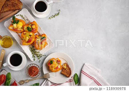 Variation of healthy breakfast with eggs baked in yellow pepper with cream cheese, ham and tomato on gray background. Food concept. copy space 118930978
