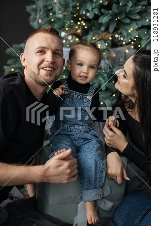 Family enjoying Christmas together by the tree indoors 118931281